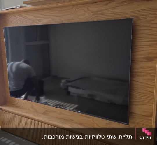 טלוויזיה מותקנת על קיר עץ בחדר מואר